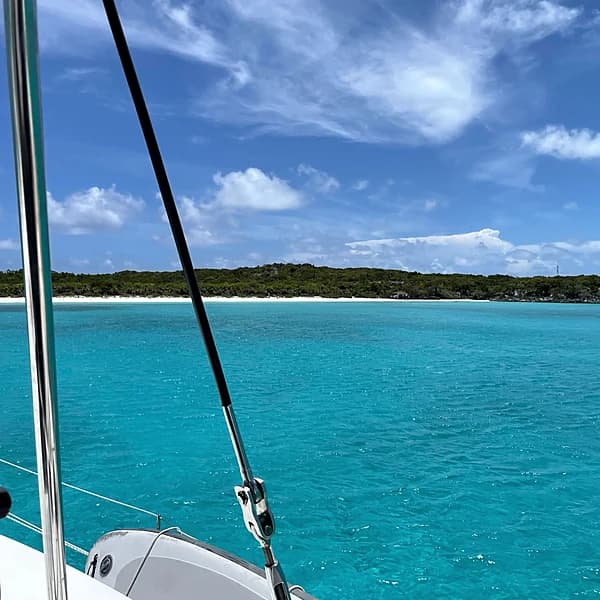 Foredeck view of a quiet Exumas anchorage with a white-sand cay beyond
