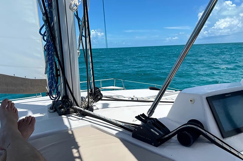At anchor in the Exumas — calm water, clear sky, the chain visible on the sand below